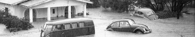 black and white image of a house and cars being flooded 