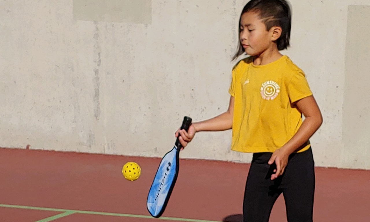 A youth playing pickleball